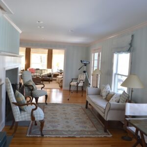 Image of the living room featuring white painted molding and sea foam wallpaper.